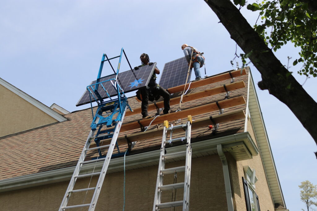 Two solar installers on a roof utilizing Safety Hoist.